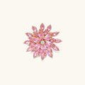 Pink cubic zirconia brooch in floral starburst design with palladium-plated copper setting on white background.
